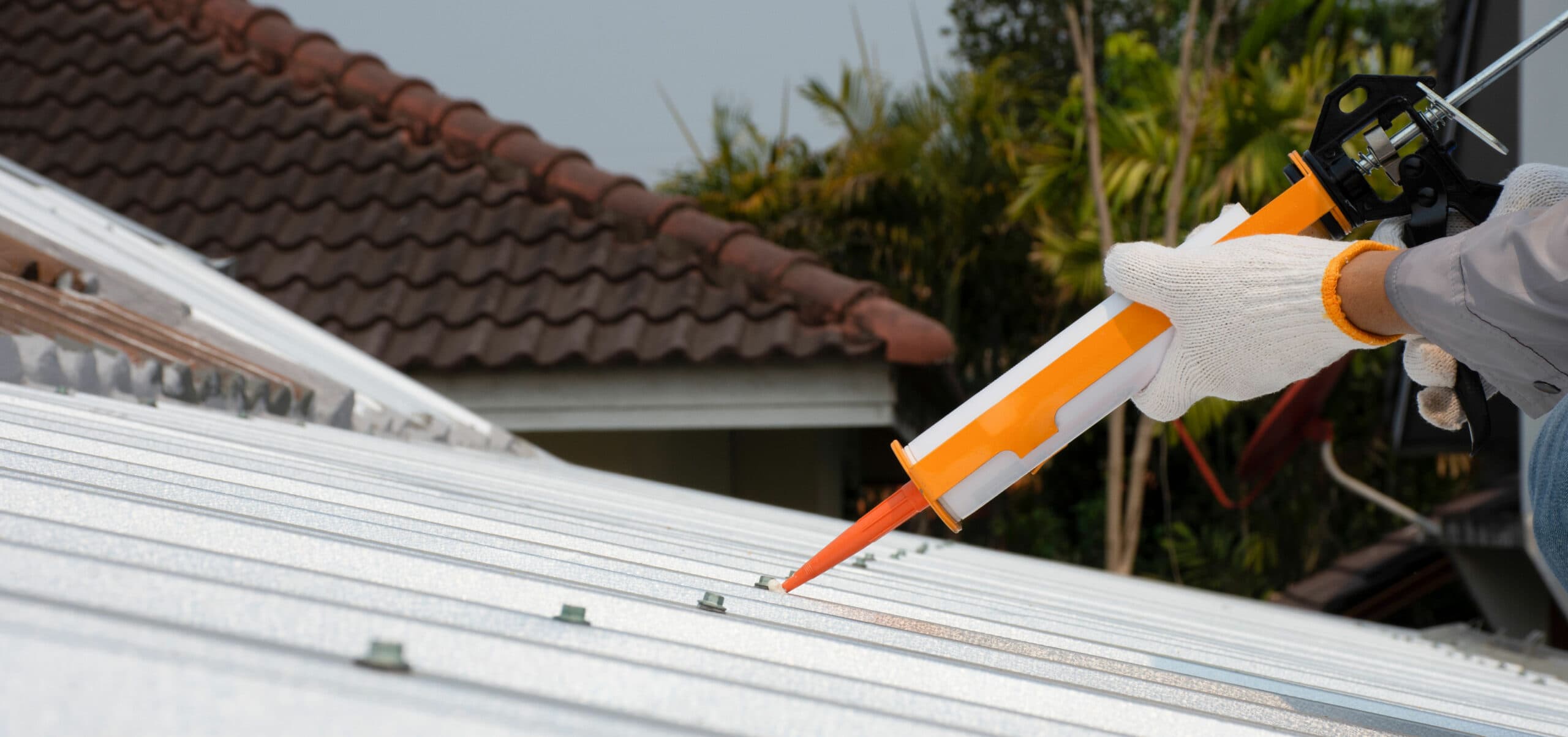 Workman sealing the flashing of a canopy against an external wall