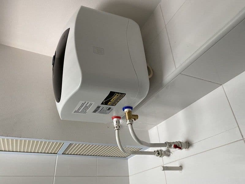 Technician installing an instant water heater in a HDB bathroom