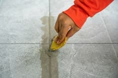 Technician replacing a cracked floor tile with a new ceramic tile