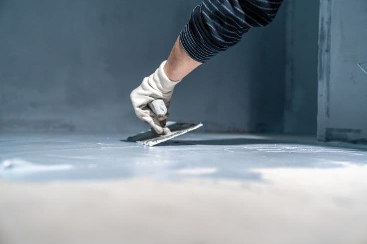 Worker sealing an external wall crack with polyurethane waterproofing