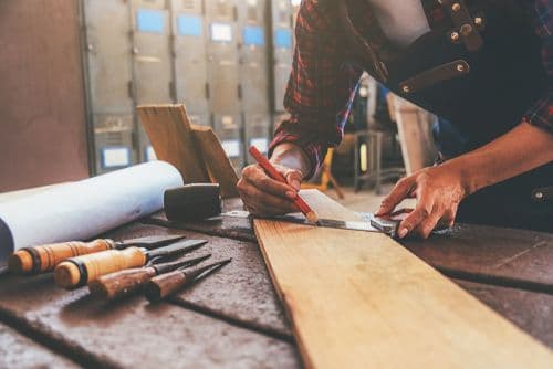 Carpenter cutting a wooden board for a custom cabinet