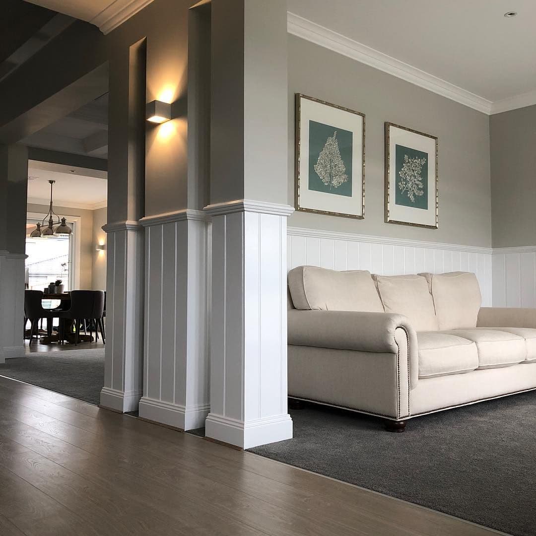 Installing white timber skirting along a painted wall