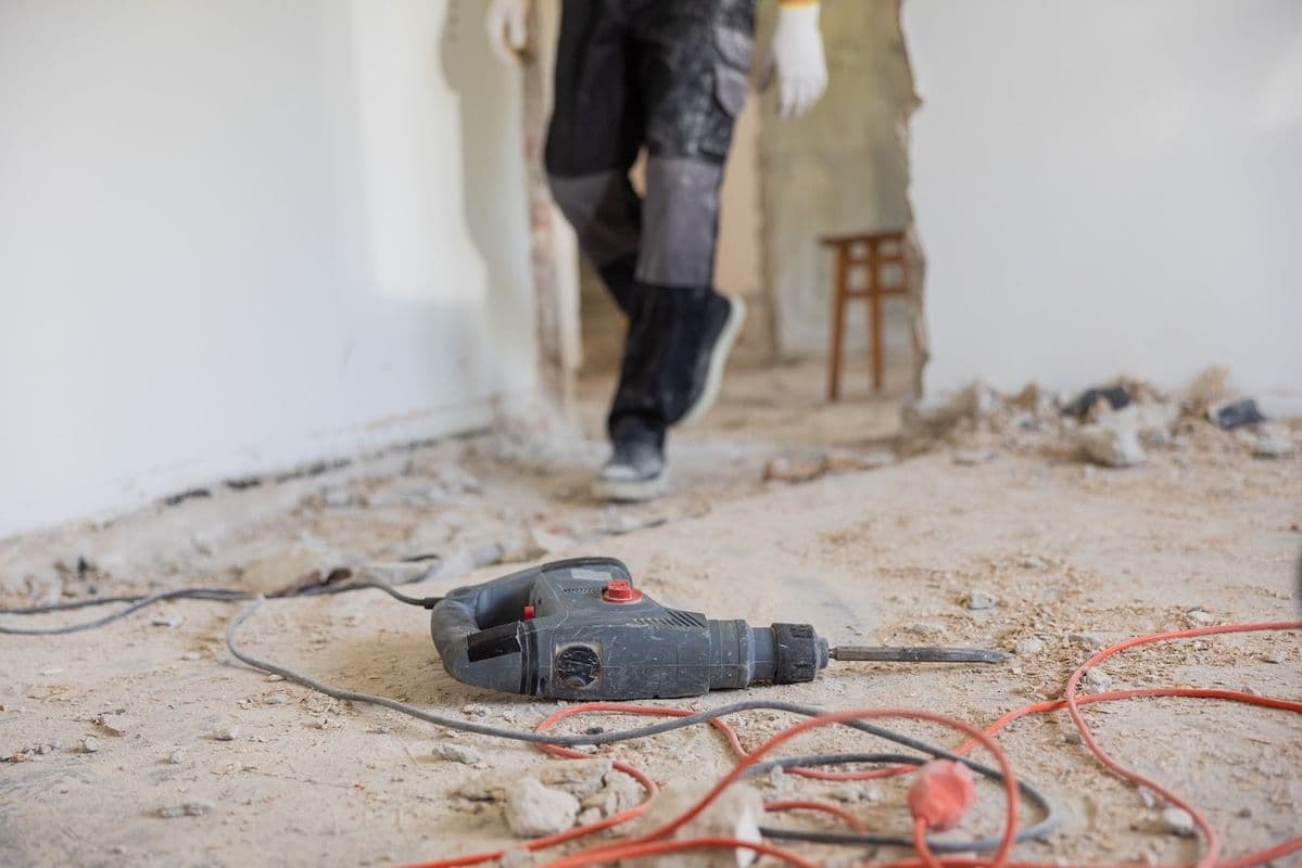 Worker hacking old floor tiles with a breaker machine