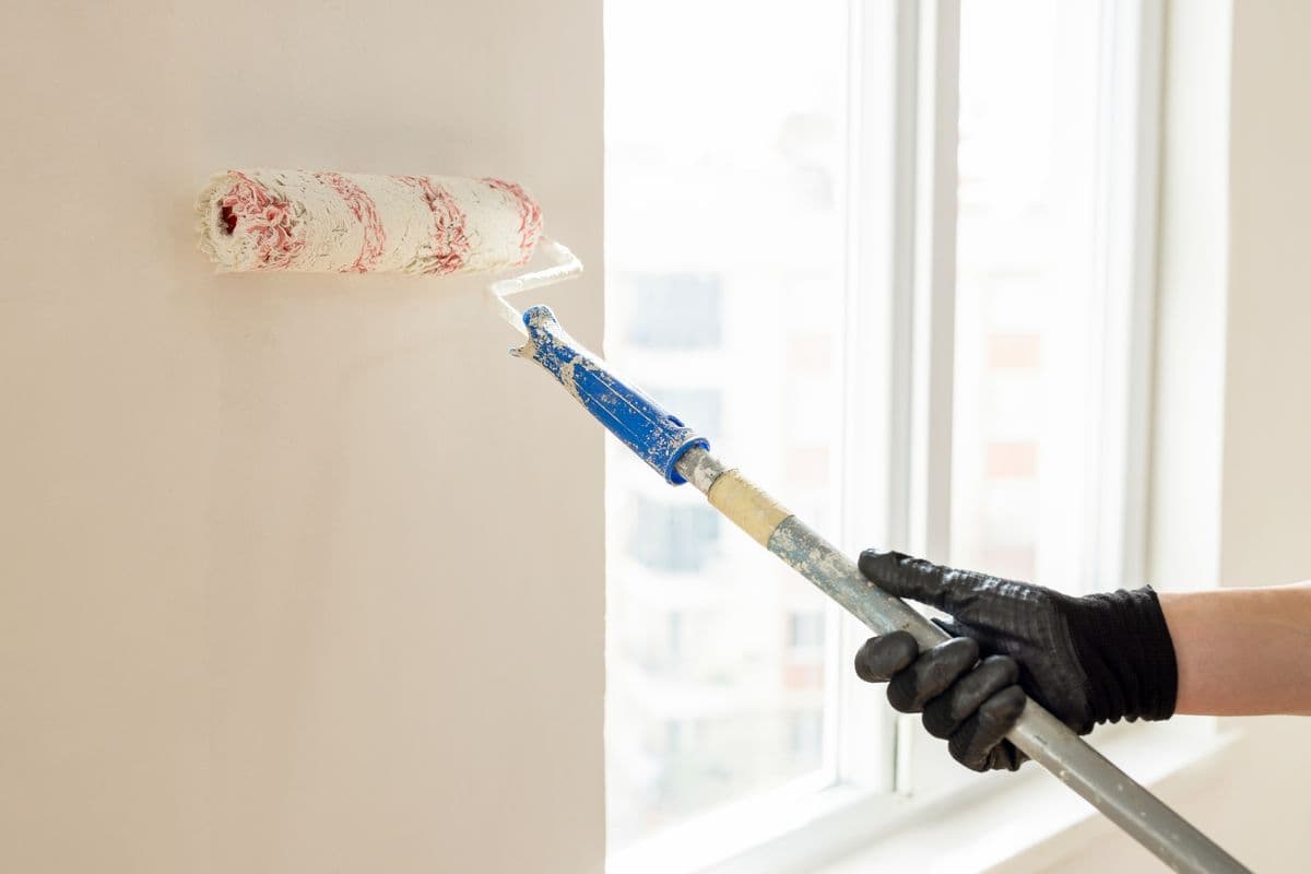 Painter rolling white emulsion on a wall