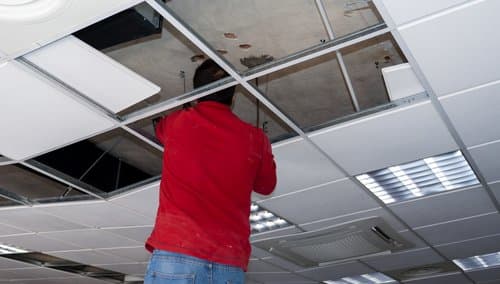 Worker installing a drywall partition in an office space